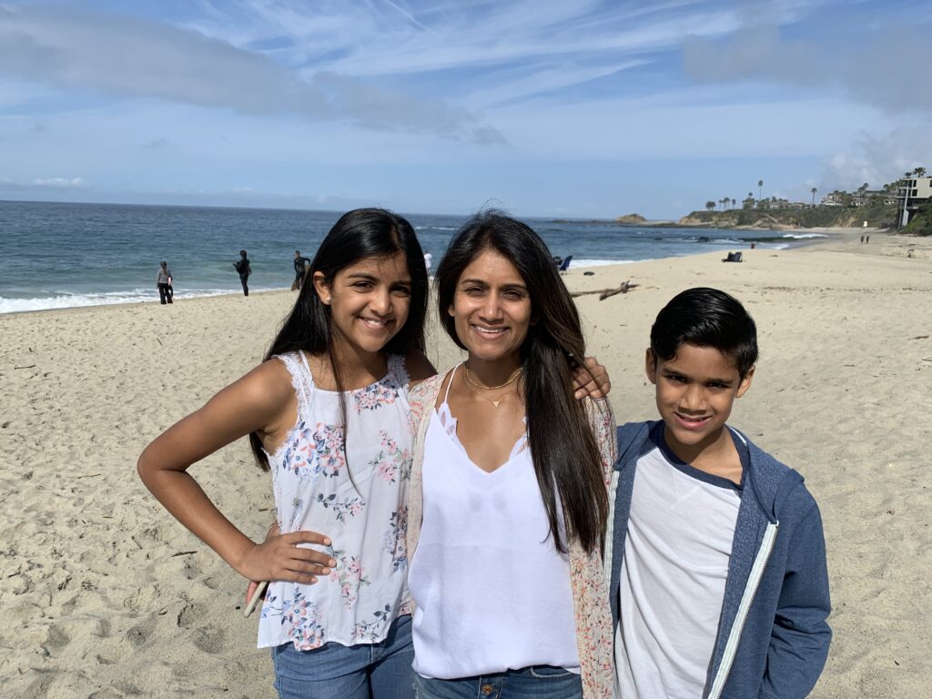 Three people standing in front of the beach smiling at the camera